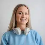 Portrait of a happy woman with headphones, wearing a blue top, smiling warmly.
